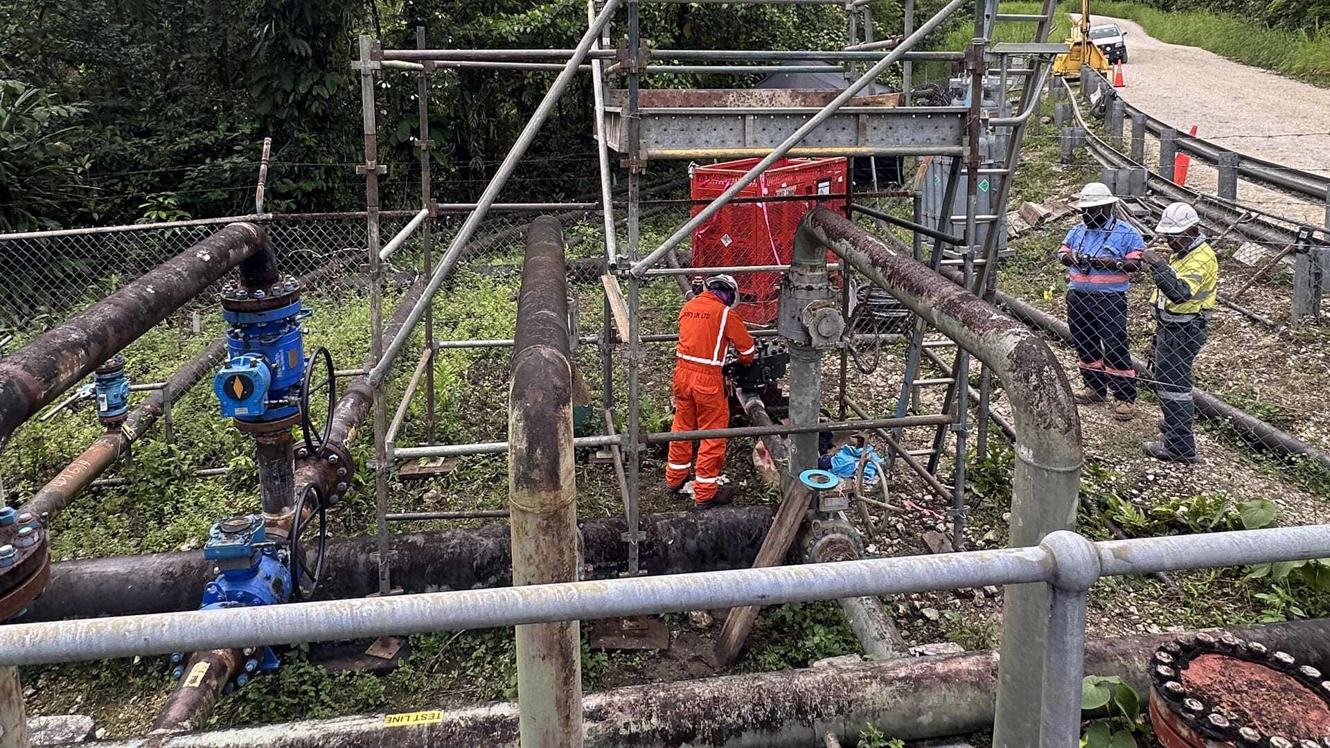 Stats Group engineer working on installing a lab valve with pipes all around him