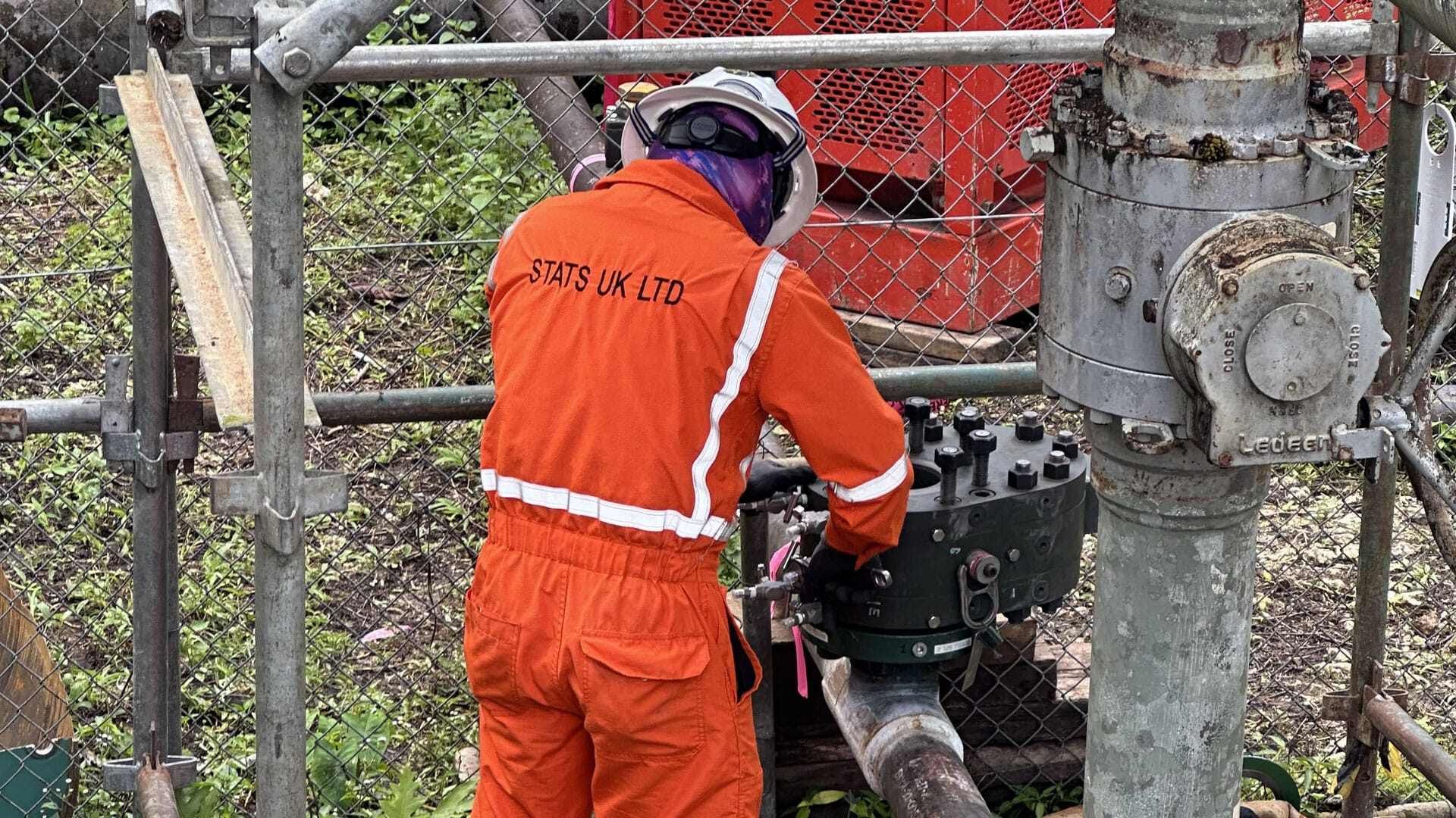 Close up of a Stats Group engineer working on installing a lab valve with pipes all around him