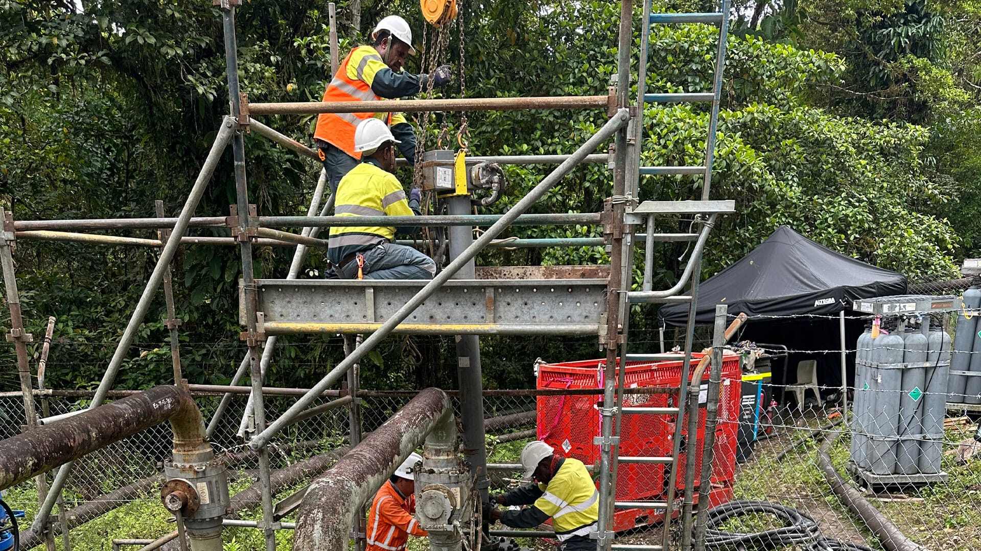 Team working on a slab valve installation surrounded by pipes and scaffolding